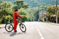 Sports and activity. Full-length portrait of a beautiful young woman in red sportswear, crossing the road on a Bicycle Royalty Free Stock Photo