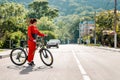 Sports and activity. Full-length portrait of a beautiful young woman in red sportswear, crossing the road on a Bicycle Royalty Free Stock Photo