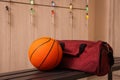 Sports bag and basketball ball on wooden bench in locker room