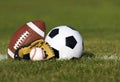 Sports balls on the field with yard line. Soccer ball, American football and Baseball in yellow glove on green grass Royalty Free Stock Photo