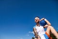 Sports and basketball concept. Young man with basketball ball in arm looking away smiling at blue sky outdoors