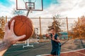 Sports and basketball. A man`s hand holds a basketball for submission. In the background, a teenager preparing to catch a ball