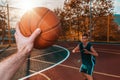 Sports and basketball. A man`s hand holds a basketball for submission. In the background, a teenager in a blur preparing to catch