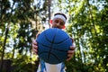 Sports and basketball. Man showing blue basketball ball in arm standing in forest looking at camera outdoors Royalty Free Stock Photo