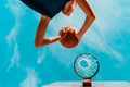 Sports and basketball. A young teenager in a blue tracksuit throws a ball into the basket. Bottom view. Blue sky in the background