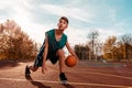 Sports and basketball. A young teenager in a green tracksuit playing basketball, leading the ball. Blue sky in the background and