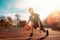 Sports and basketball. A young teenager in a green tracksuit playing basketball, leading the ball. Blue sky in the background and