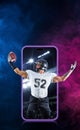 Sports betting on american football. Sportsman with ball in helmet on stadium in action. Bets in the mobile application Royalty Free Stock Photo