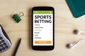 Sports betting concept on smart phone screen on wooden desk