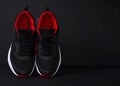 Sports black sneakers with red accents on a black table.