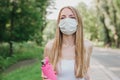 Sports blonde girl in a white medical mask jogging in the park healthy lifestyle during quarantine covid-19