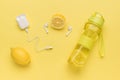 A sports bottle with water and lemon and wireless headphones on a yellow background Royalty Free Stock Photo