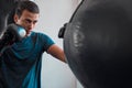 Sports, boxing and man with punching bag in gym for training, exercise or workout. Boxer, athlete and male fighter punch