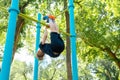 Sports boy performs a coup on the horizontal bar in the park Royalty Free Stock Photo