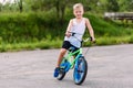 Sports boy of seven years in a white t-shirt riding a two-wheeled bike on the pavement in the summer Royalty Free Stock Photo