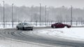 Sports cars drive through a turn on a snow-covered slippery highway.