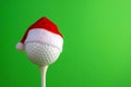 Sports concept on the topic of golf, Christmas and New Year. White golf-ball in a red Santa Claus hat set on a tee. Green Royalty Free Stock Photo