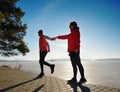 Sports couple crazy jumping on park path around frozen lake