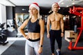 Sports couple, young woman and man in Santa Claus hats in sportswear, work out in the gym, sports concept, New Year