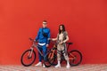 Sports couple in sportswear with bicycles stand on the background of a red wall and look at the camera. Cycling Royalty Free Stock Photo