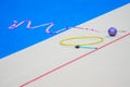 Sports equipment for rhythmic gymnastics lie on the edge of the carpet in the gym. Rhythmic gymnastics clubs, a ball, a hoop Royalty Free Stock Photo