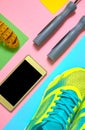 Sports equipment with running shoes, skipping rope, mobile phone with black screen and measuring tape on colorful background. Royalty Free Stock Photo