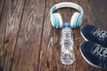 Sports equipment. Sneakers, water and headphones on wooden background