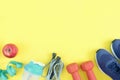 Sports equipment on a yellow background. Dumbbells, rope, bottle and sneakers are beautifully spread out. Fitness