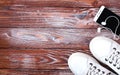 Sports flatlay with white sneakers, earphone and phone on wooden background. Concept healthy lifestyle. Top view. Copy space