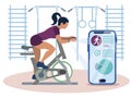 Sports gadget. A woman doing a workout on a bike-trainer and using a mobile application to watch out her performance