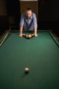 Sports game of billiards on a green cloth. Millennial man putting multi-colored billiard balls in the form of a triangle Royalty Free Stock Photo