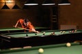 Sports game of billiards on a green cloth. Woman playing with Multi-colored billiard balls and cue on a pool table Royalty Free Stock Photo