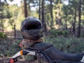 Sports Gear, a crash helmet and gear bag, on an Adventure Motorcycle parked out in a forest.