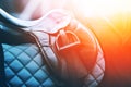 Sports gear worn on the horse - stirrup, leather saddle and blue saddlecloth are illuminated by sunlight Royalty Free Stock Photo