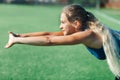 Sports girl in a blue shirt and leggings doing gymnastics workout on a football field. Fitness, sport, health energy. Close up. Royalty Free Stock Photo