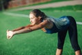 Sports girl in a blue shirt and leggings doing gymnastics workout on a football field. Fitness, sport, health energy. Royalty Free Stock Photo