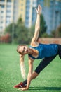 Sports girl doing in a blue shirt and leggings gymnastics workout on a football field. Fitness, sport, health energy. Royalty Free Stock Photo