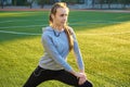 Sports girl doing morning gymnastics workout on green grass. In the control of warm sunlight. Fitness, sport, health, energy. Royalty Free Stock Photo