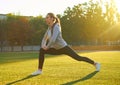 Sports girl doing morning gymnastics workout on green grass. In the control of warm sunlight. Fitness, sport, health, energy. Royalty Free Stock Photo