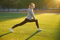 Sports girl doing morning gymnastics workout on green grass. In the control of warm sunlight. Fitness, sport, health, energy. Royalty Free Stock Photo