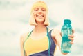 Sports girl drinks water from a bottle on a sky background. Drinking during sport. Woman in sportswear is holding a Royalty Free Stock Photo