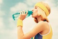 Sports girl drinks water from a bottle on a sky background. Healthy lifestyle concept. Drinking during sport. Young Royalty Free Stock Photo