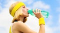 Sports girl drinks water from a bottle on a sky background. Healthy lifestyle concept. Drinking during sport. Young Royalty Free Stock Photo