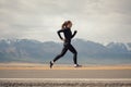 Sports girl is engaged in jogging on the highway against the background of mountains