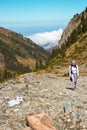 A sports girl travels in the mountains. Clouds in the blue sky