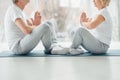 Sports and healthy lifestyle. Croppes image of sporty middle aged couple sitting on the mat in the white fitness gym and doing Royalty Free Stock Photo