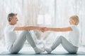 Sports and healthy lifestyle.Sporty middle aged couple sitting on the mat in the white fitness gym and doing stretching while