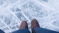 Sports Hiking warm shoes on the feet of the traveler. The tourist stands on the beautiful ice with bubbles on lake Baikal