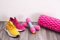 Sports at home - sneakers of different colors, dumbbells and a massage roller