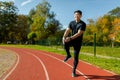 Sports injury. A young male athlete stands on a running track in a stadium and holds his leg, his knee. Crouching from Royalty Free Stock Photo
